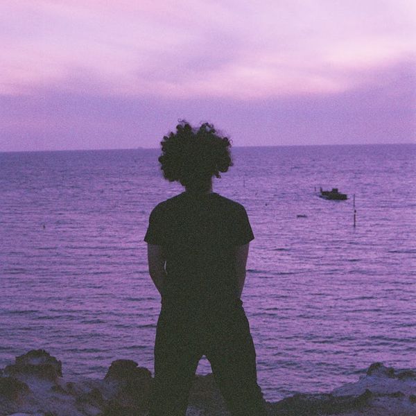 Person meditating outdoors with a sunrise in the background.